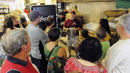 Participants on a 'Burgh Bits & Bites food tour of the Strip District listen to Erin Hodgkiss discuss the breadmaking process at Mancini's.