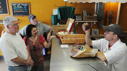 Casey Romig, right, a butcher at Parma Sausage in the Strip District, holds up venito and explains what Greg Moniuszko, left, Melissa Morris and Jeff Collins are sampling.