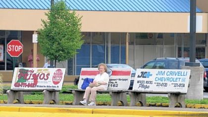 A woman sits on a bench on Chartiers Avenue in McKees Rocks on Friday.