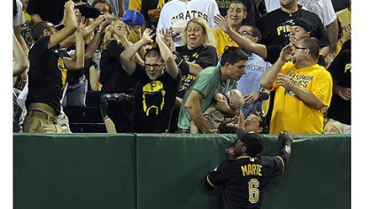 Pirate fans grab a two-run home run ball hit by Padres' Chase Headley as Pirates' Starling Marte climbs the outfield wall in the seventh inning Friday night at PNC Park.