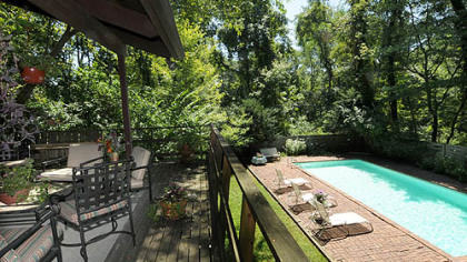 A covered rear deck looks out over the pool and wooded yard.