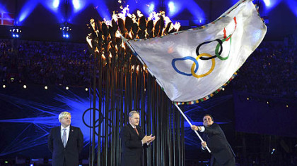 London Mayor, Boris Johnson, left, watches the Mayor of Rio de Janeiro, Eduardo Paes, right, wave the Olympic flag as the International Olympic Committee President Jacques Rogge applauds during the Closing Ceremony of the 2012 Summer Olympics.