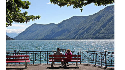 A couple takes in the view from the promenade, Lago Lugano, Switzerland.