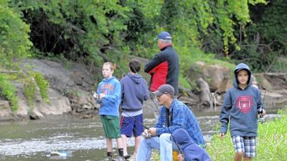 Contestants on Saturday in Heidelberg's first fishing tournament along Chartiers Creek included Bill Puccio of Scott, sitting, and his sons, David Puccio, 11, squatting next to his father, and Tyler Puccio, 9, at far right.